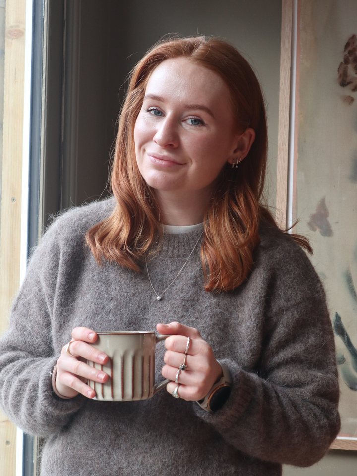 Claudia at home in her cottage holding a mug