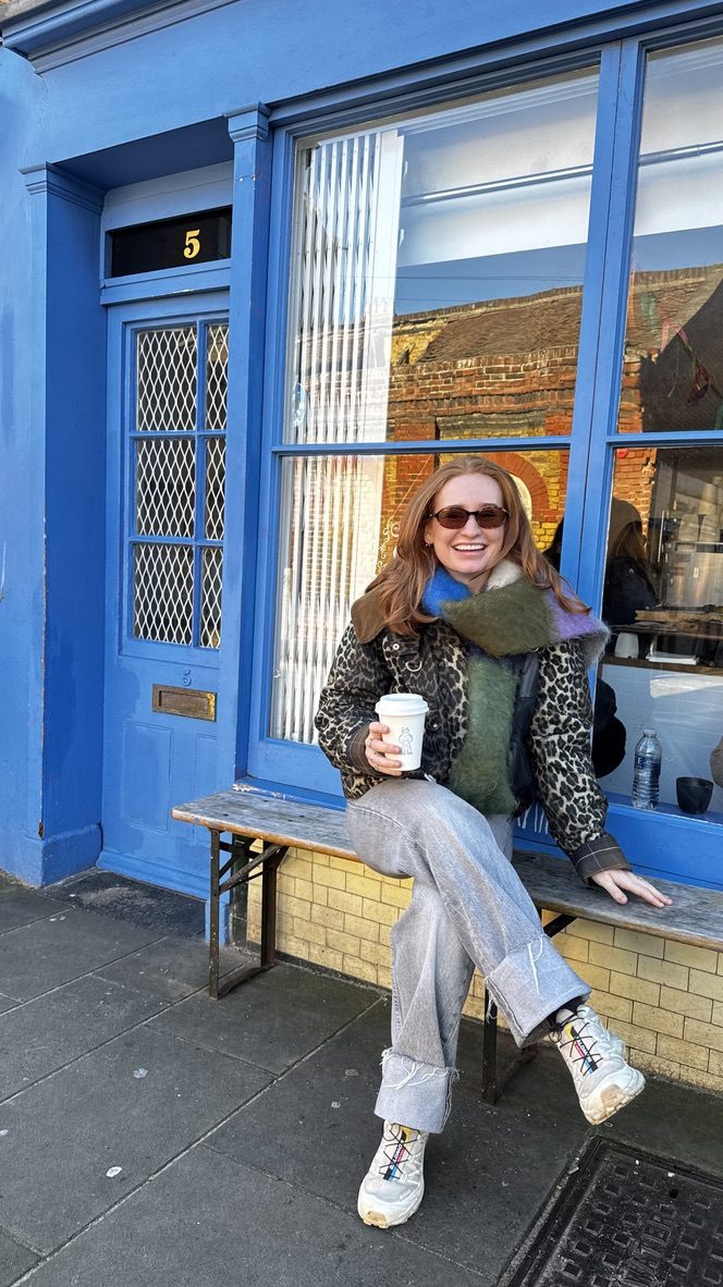 Claudia sitting outside a café with a coffee
